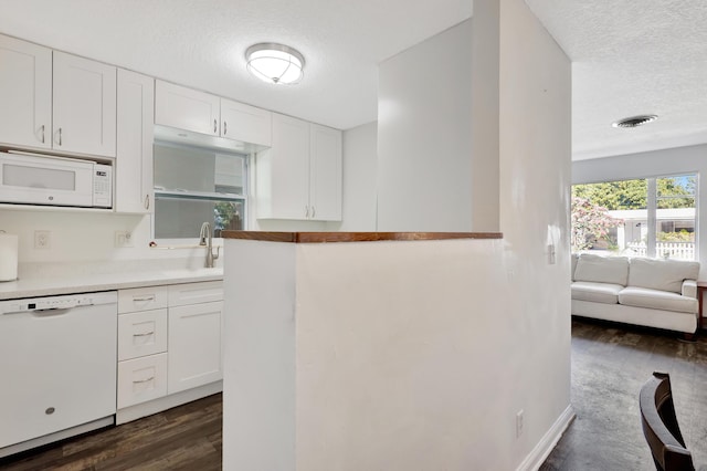 kitchen with sink, white cabinetry, a textured ceiling, dark hardwood / wood-style flooring, and white appliances