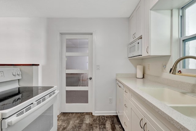 kitchen with sink, white appliances, dark hardwood / wood-style floors, light stone counters, and white cabinets