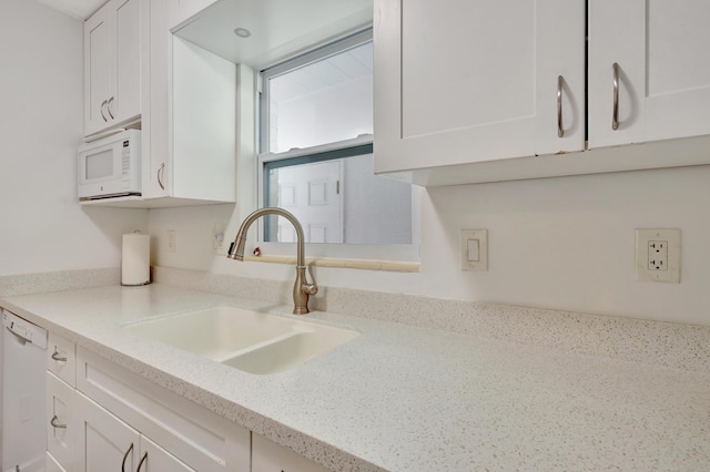 kitchen with light stone counters, white appliances, sink, and white cabinets