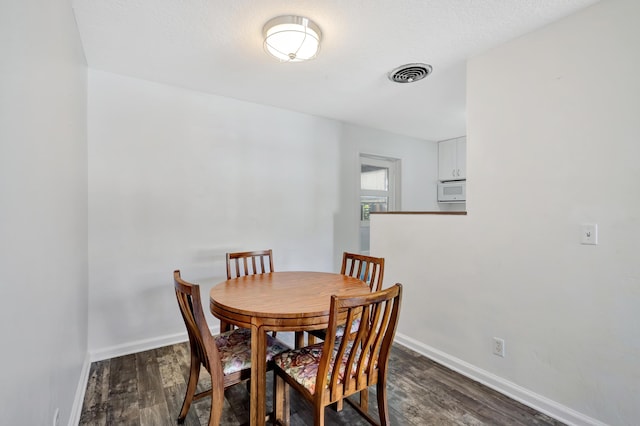 dining area with dark hardwood / wood-style flooring and a textured ceiling