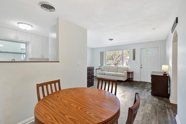 dining room with dark wood-type flooring and a textured ceiling