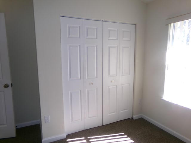 unfurnished bedroom featuring dark carpet and a closet