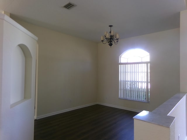 spare room featuring dark hardwood / wood-style flooring and a notable chandelier