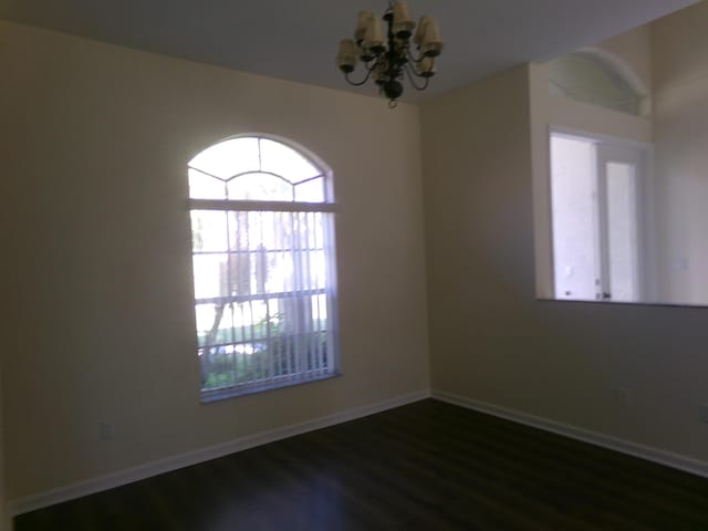 unfurnished room featuring dark hardwood / wood-style flooring and a notable chandelier