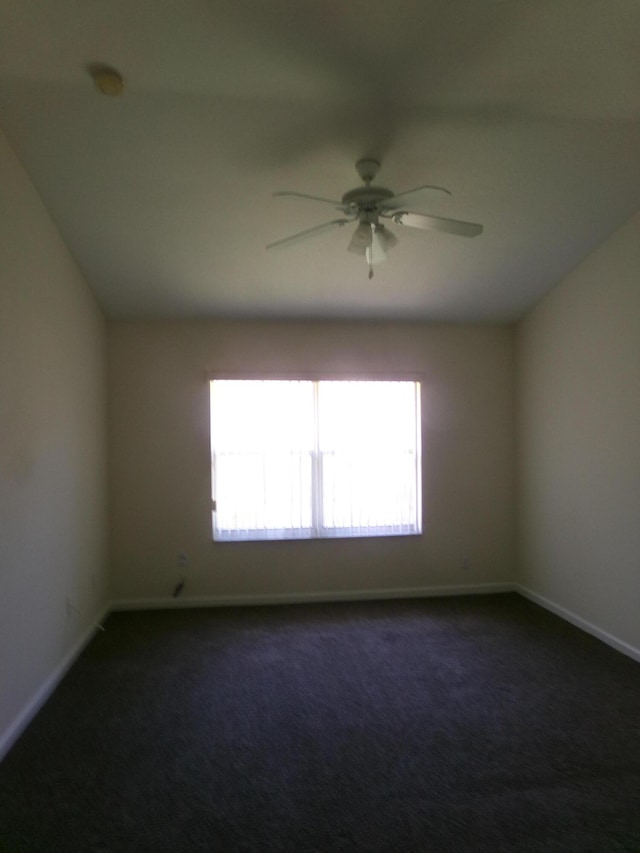 spare room with dark colored carpet, plenty of natural light, and ceiling fan