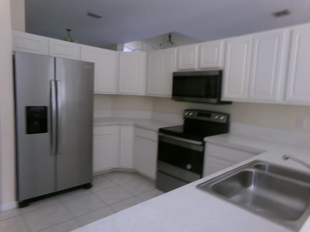 kitchen with light tile patterned flooring, white cabinetry, sink, and appliances with stainless steel finishes