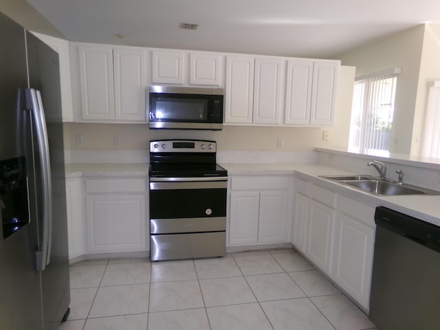 kitchen with white cabinetry, sink, light tile patterned floors, and stainless steel appliances