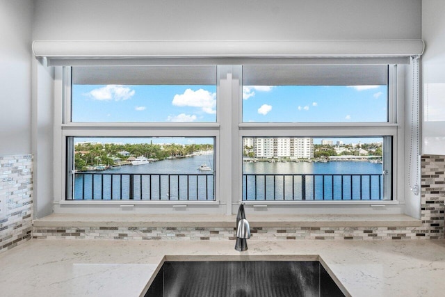 interior details with light stone countertops, sink, and a water view