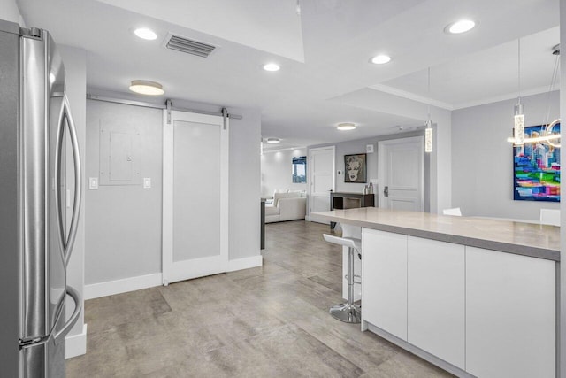 kitchen featuring stainless steel fridge, ornamental molding, pendant lighting, a barn door, and white cabinets