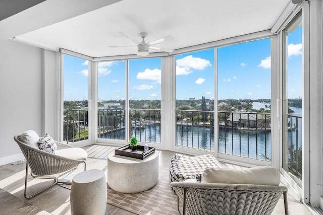 sunroom with plenty of natural light, ceiling fan, and a water view