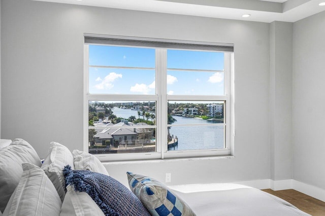 bedroom with a water view and wood-type flooring