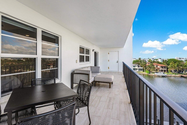 balcony with an outdoor living space and a water view