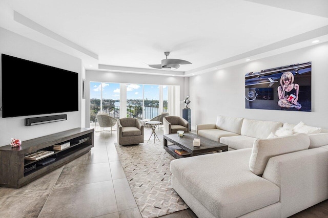 living room with ceiling fan and a tray ceiling