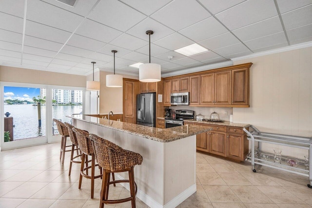 kitchen with hanging light fixtures, a kitchen breakfast bar, stone countertops, a water view, and appliances with stainless steel finishes