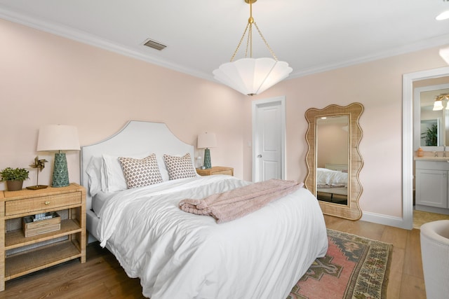 bedroom with crown molding, ensuite bath, and wood-type flooring