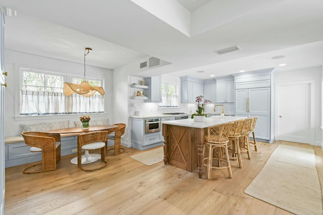 kitchen featuring a kitchen island, decorative light fixtures, decorative backsplash, paneled built in refrigerator, and light hardwood / wood-style floors