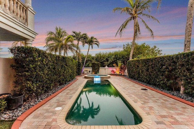 pool at dusk with an in ground hot tub