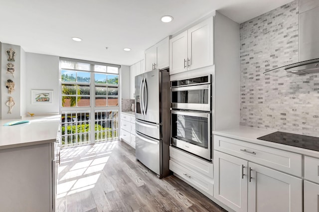 kitchen with tasteful backsplash, light wood finished floors, light countertops, appliances with stainless steel finishes, and white cabinetry