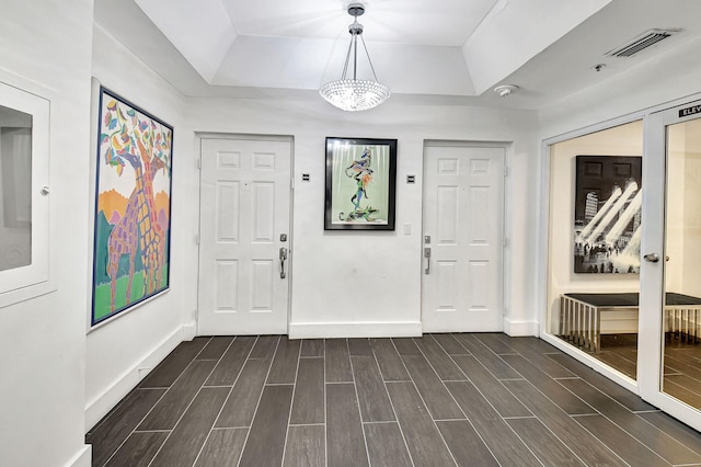 foyer entrance with a chandelier and a tray ceiling