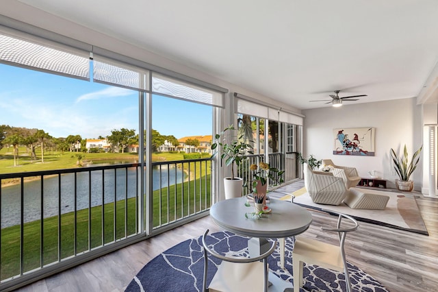 sunroom featuring ceiling fan and a water view