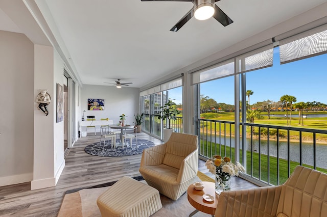 sunroom / solarium with a ceiling fan and a water view