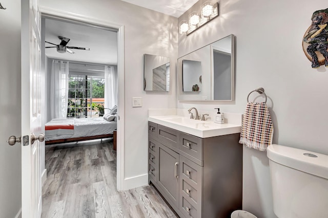 ensuite bathroom featuring toilet, ensuite bath, wood finished floors, ceiling fan, and vanity