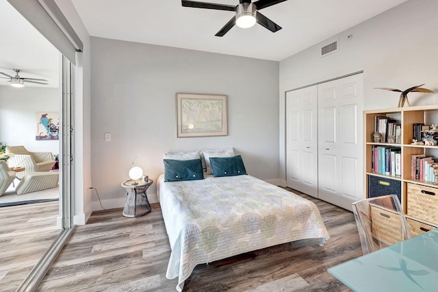 bedroom featuring wood finished floors, baseboards, visible vents, ceiling fan, and a closet