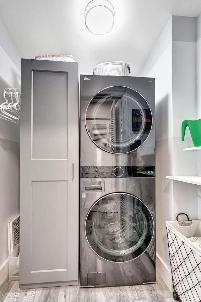 clothes washing area with stacked washing maching and dryer and light hardwood / wood-style floors