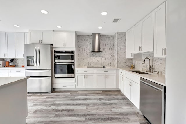 kitchen with visible vents, a sink, stainless steel appliances, light countertops, and wall chimney exhaust hood