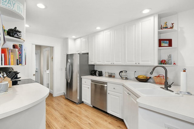 kitchen with appliances with stainless steel finishes, light hardwood / wood-style floors, white cabinetry, and sink