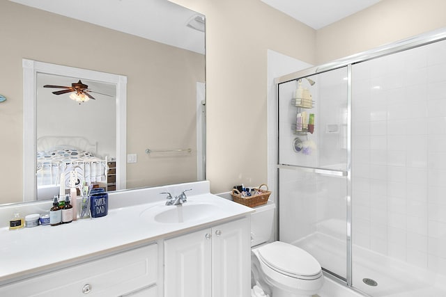 bathroom featuring vanity, toilet, a shower with door, and ceiling fan