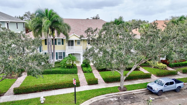 view of front of house featuring a balcony and a front lawn