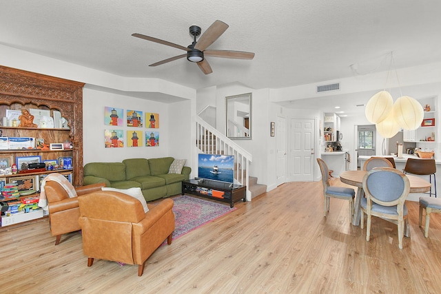 living room with ceiling fan, light hardwood / wood-style flooring, and a textured ceiling