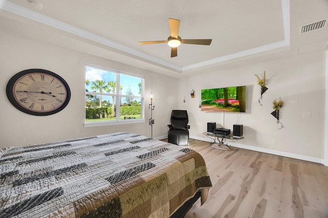 bedroom with a raised ceiling, ceiling fan, crown molding, and wood-type flooring