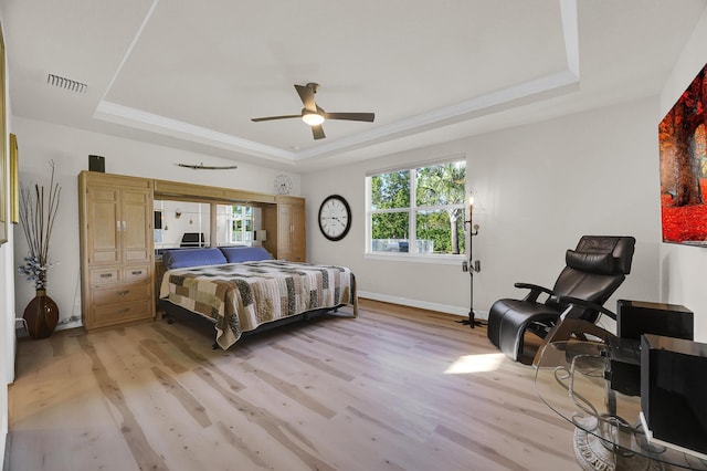 bedroom with ceiling fan, a tray ceiling, and multiple windows