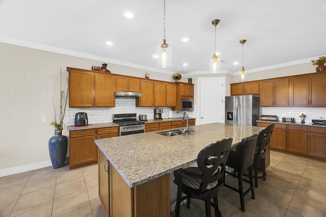 kitchen with sink, hanging light fixtures, stainless steel appliances, and a kitchen island with sink