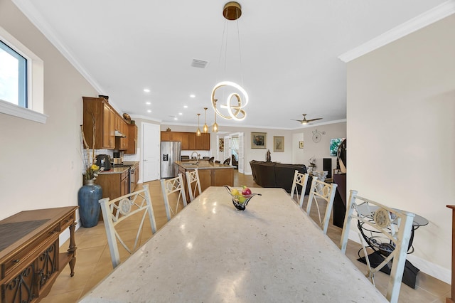 tiled dining room with sink, ceiling fan with notable chandelier, and ornamental molding