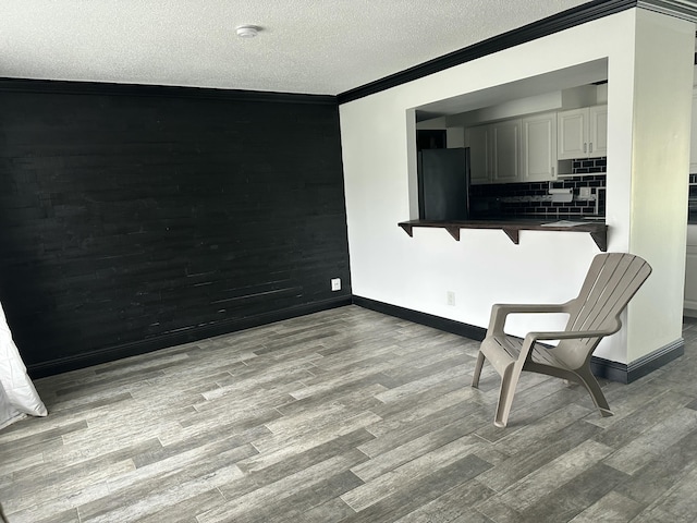 sitting room featuring light wood-type flooring, a textured ceiling, and ornamental molding