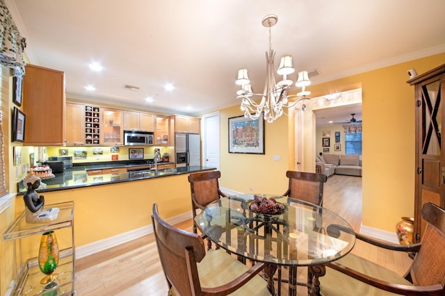 dining area with crown molding, a notable chandelier, sink, and light wood-type flooring