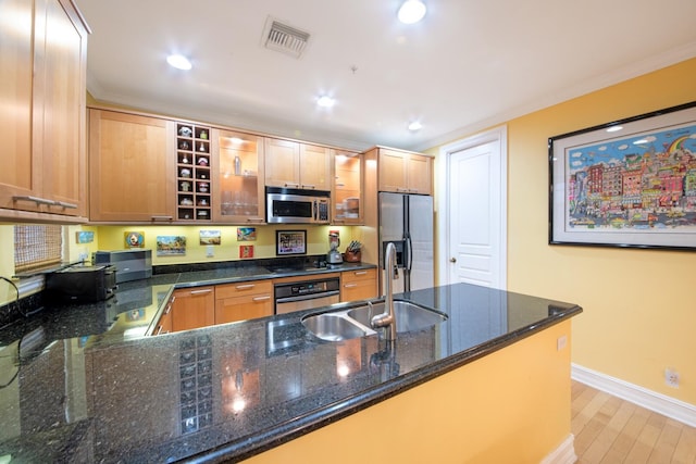 kitchen featuring sink, dark stone countertops, light hardwood / wood-style floors, kitchen peninsula, and stainless steel appliances