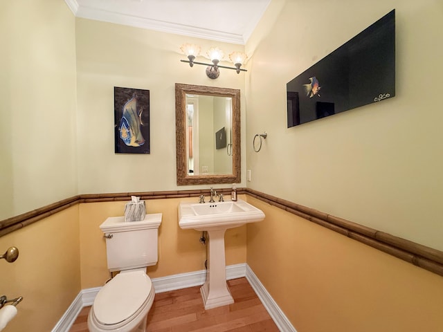 bathroom featuring crown molding, hardwood / wood-style floors, and toilet