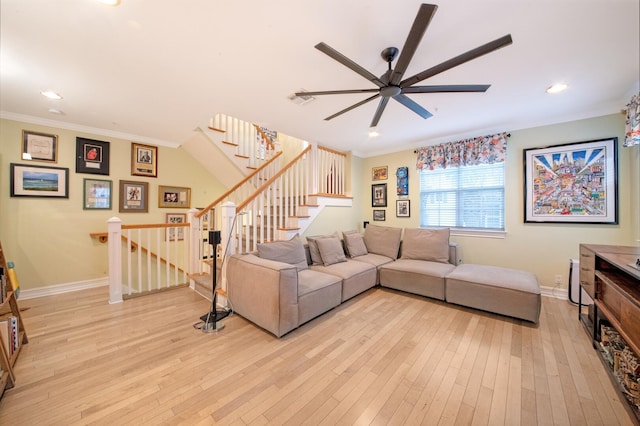 living room featuring stairs, light wood-style flooring, baseboards, and ornamental molding