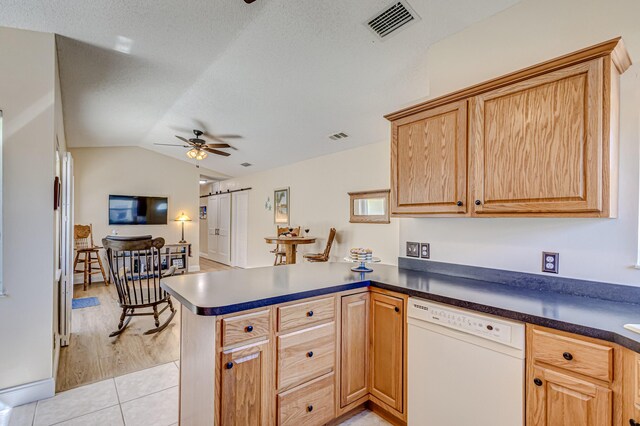 kitchen featuring ceiling fan, dishwasher, kitchen peninsula, lofted ceiling, and light tile patterned floors