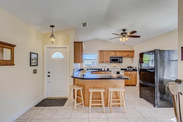 kitchen featuring ceiling fan, a kitchen breakfast bar, lofted ceiling, light tile patterned flooring, and black appliances