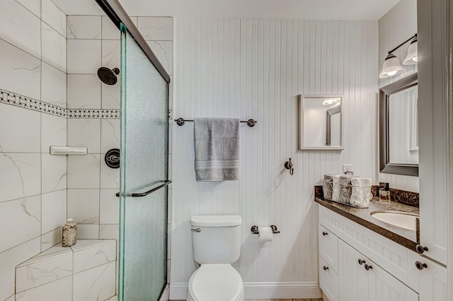 bathroom featuring vanity, toilet, and a shower with door