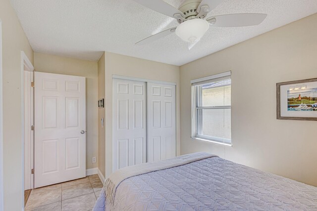 bedroom featuring ceiling fan, light tile patterned flooring, a textured ceiling, and a closet