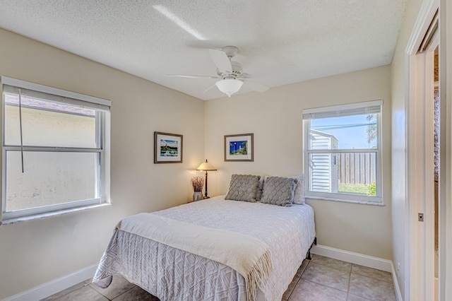 tiled bedroom featuring ceiling fan and a textured ceiling