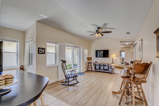 living room featuring a textured ceiling, plenty of natural light, lofted ceiling, and light hardwood / wood-style flooring