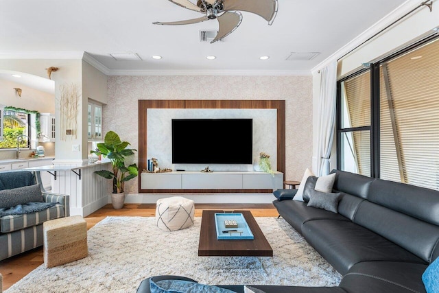 living room featuring ceiling fan, light wood-type flooring, and ornamental molding