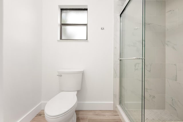 bathroom with hardwood / wood-style floors, a shower with shower door, and toilet